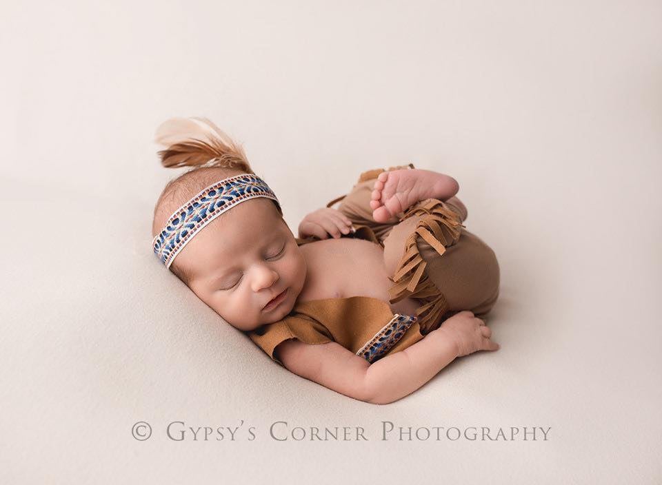 Tan faux suede fringe leggings and tribal ribbon headband with feather, posed on sleeping newborn, cream backdrop.