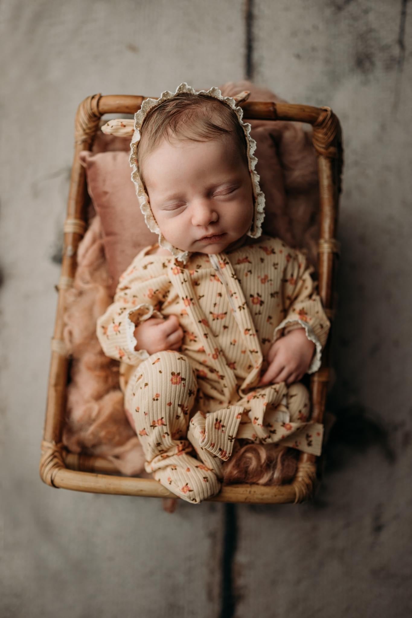 Sleeping newborn wearing handmade fall floral romper with matching bonnet, vintage-inspired photo prop outfit, Lily Mily Boutique.